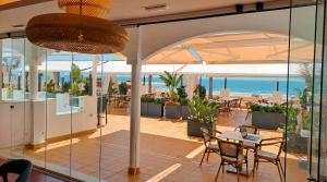 a restaurant with a table and chairs and a view of the ocean at Hotel Vértice Chipiona Mar in Chipiona