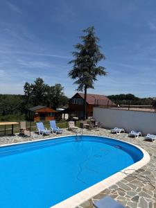 a large blue swimming pool with chairs and a house at Kosmaj Thalia in Babe
