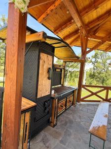 an outdoor grill on a patio with a wooden roof at Kosmaj Thalia in Babe