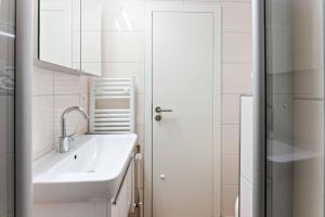 a white bathroom with a sink and a mirror at Lütt Mööv in Wenningstedt +26 photos