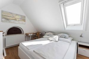 a white bedroom with a bed and a window at Lütt Mööv in Wenningstedt