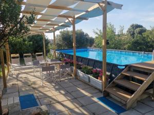 a pergola over a swimming pool with a table and chairs at Profumo Di Terra in Monopoli