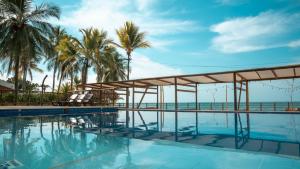 a swimming pool with palm trees and the ocean at Cabañas La Española in Coveñas