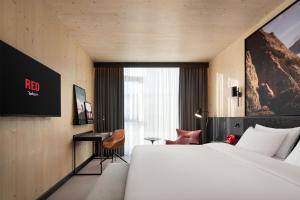 a hotel room with a large bed and a desk at Radisson RED Innsbruck in Innsbruck