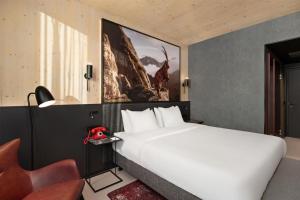 a bedroom with a large white bed and a chair at Radisson RED Innsbruck in Innsbruck +90 photos