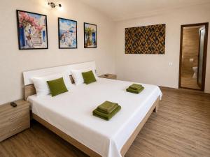a bedroom with a large white bed with green pillows at Vila Manila in Eforie Nord