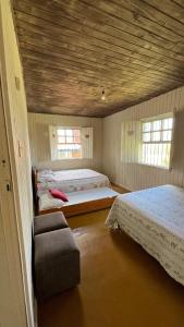 a bedroom with two beds and a chair in it at Sítio Espírito Santo in Paraisópolis