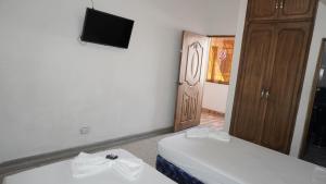 a room with two beds and a television and a door at Hogar de Paso Santa Teresa in Cúcuta