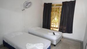 two beds in a room with a window at Hogar de Paso Santa Teresa in Cúcuta
