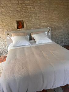 a white bed with two pillows in a bedroom at La chambre des clefs in Ranville