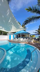 a swimming pool with a beach house and palm trees at El Tridente in Juan Dolio