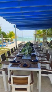 a long table with chairs and a blue umbrella on a beach at El Tridente in Juan Dolio