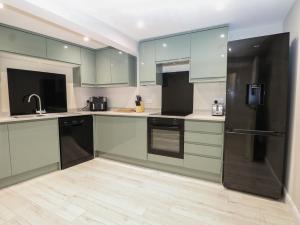 a kitchen with green cabinets and a black refrigerator at 2 Bed in Southampton