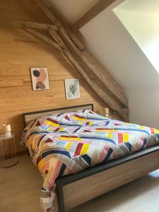 a bed with a colorful comforter in a attic at Gîte Les Jacquets in Hautefort