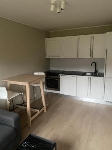 a kitchen with white cabinets and a table and a couch at Appartment in Jørpeland