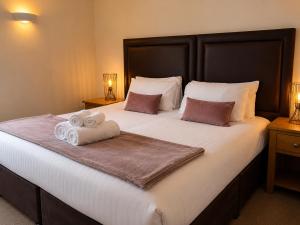 a bedroom with a large bed with towels on it at Stratford Limes Hotel in Stratford-upon-Avon