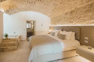 a bedroom with a large bed and a stone wall at Tenuta Legaro in Cozzana