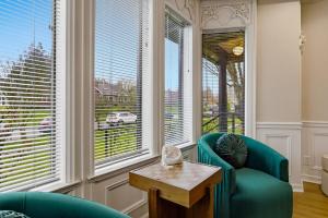 a living room with a green chair and a table and windows at Spacious Proctor Tudor-Sleeps 16-Dog Friendly-Walk in Tacoma