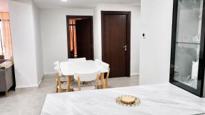 a white dining room with a white table and chairs at Appart Ilyani in El Kseur +1 photo