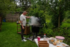 a man cooking food on a grill in a yard at Casa Lilou in Lochristi