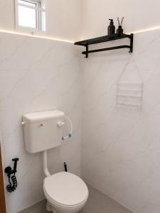 a white bathroom with a toilet and a window at Dmana Homestay Arau Perlis Tiny House in Arau