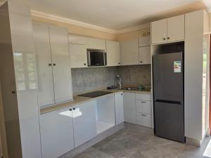 a kitchen with white cabinets and a refrigerator at Sea & Forest Self Catering Estate - Durban Kingsburgh in Kingsborough +25 photos
