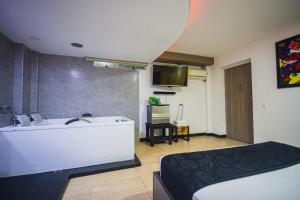 a bathroom with a tub and a sink and a bed at Hotel Kalifornia in Bello +27 photos