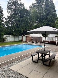 a picnic table with an umbrella next to a pool at Brookswood Oasis - Guest suite,1 bedroom,1 den & 1 full bathroom in Langley
