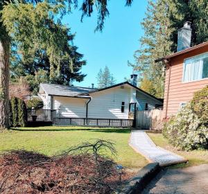 a white house with a fence in a yard at Brookswood Oasis - Guest suite,1 bedroom,1 den & 1 full bathroom in Langley