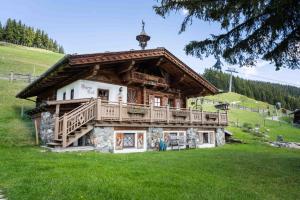 a log cabin with a balcony on a green field at Panorama Alm Chalets by we rent JOKERCARD INCLUDED in Saalbach-Hinterglemm