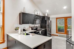 a kitchen with black cabinets and a white counter top at House Juniper in Tannersville
