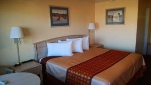 Habitación de hotel con cama grande con almohadas blancas en White Sands Motel, en Alamogordo