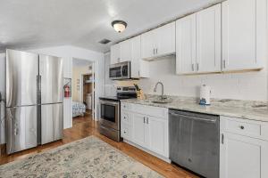 a kitchen with white cabinets and a stainless steel refrigerator at Sanibel Sandals & Flip Flops in Sanibel