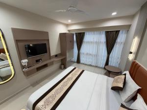 a hotel room with a bed and a tv at Hotel Prime Divine in Ahmedabad