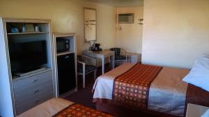 a hotel room with two beds and a television at White Sands Motel in Alamogordo