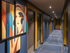 ein Korridor mit Gemälden einer Frau an der Wand in der Unterkunft ibis Styles Saint-Quentin in Saint-Quentin