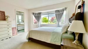 a white bedroom with a bed and a window at Ocean View Home Nanaimo in Nanaimo