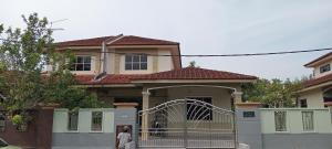 a woman standing in front of a house with a gate at kluanghomestayvilla in Kluang