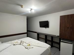 a bedroom with a bed with a tv on the wall at Pousada Fecep in Guaratuba +18 photos