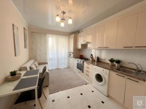 a kitchen with white cabinets and a table and a sink at RentHouse Apartments Cozy Stay in Chişinău