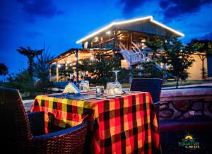 a table with glasses on it in front of a house at Equator Lodge & Campsite in Kikorongo