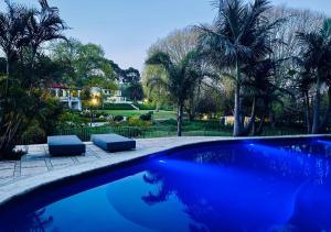 a blue swimming pool with two chairs and palm trees at Homestead Villas in Bellville