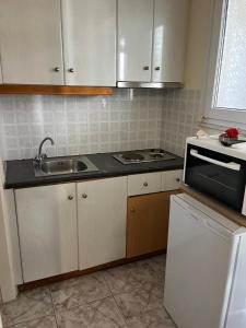a kitchen with a sink and a stove and a microwave at Stella Maris sea front studios in Kanatádhika