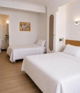 two beds in a hotel room with white walls at Hôtel le Canetois in Canet-en-Roussillon +10 photos