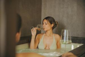 a woman in a bathtub drinking a glass of wine at Evangelisti Palace in Bellaria-Igea Marina