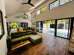a living room with a green couch and large windows at Between Waves and Woods in Sámara