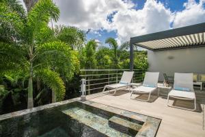 a patio with two chairs and a swimming pool at Karibu House in Les Trois-Îlets
