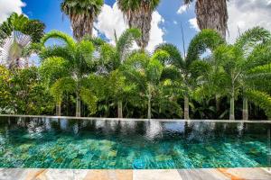 a swimming pool with palm trees in the background at Karibu House in Les Trois-Îlets