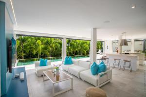 a living room with a white couch and blue pillows at Karibu House in Les Trois-Îlets