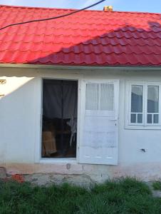a white house with a red roof and a window at Căsuța de vacanță in Bogata